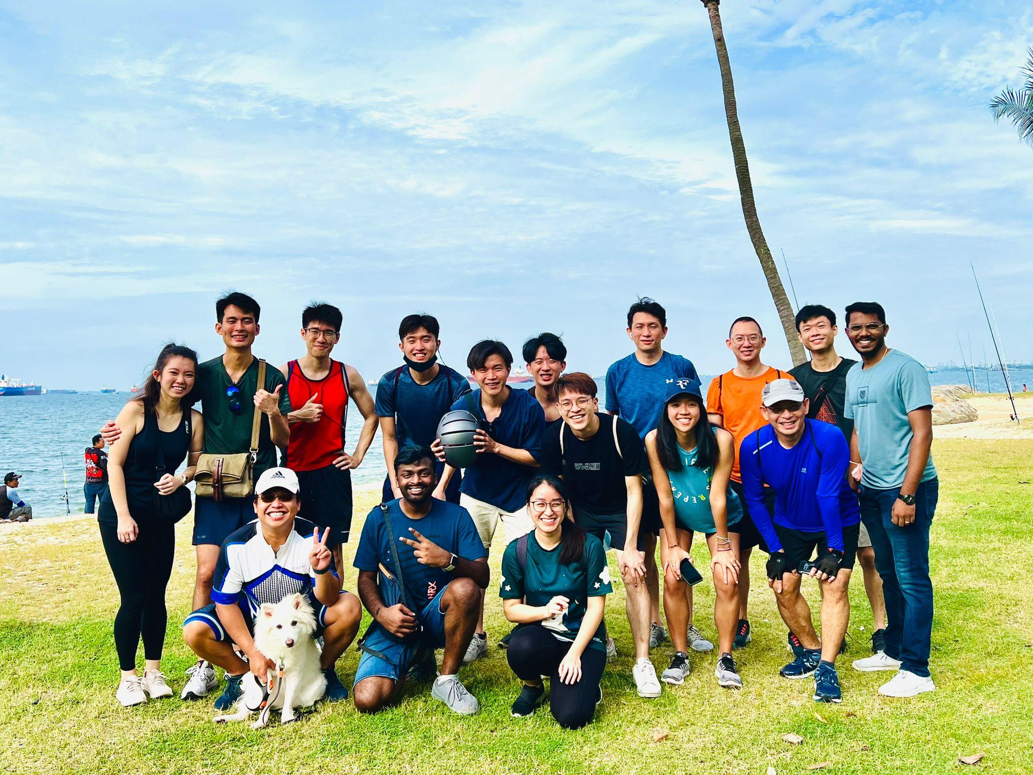 SimplifyNext team members posing for a photo at the seaside, standing on vibrant green grass. One of the members is holding a white dog.